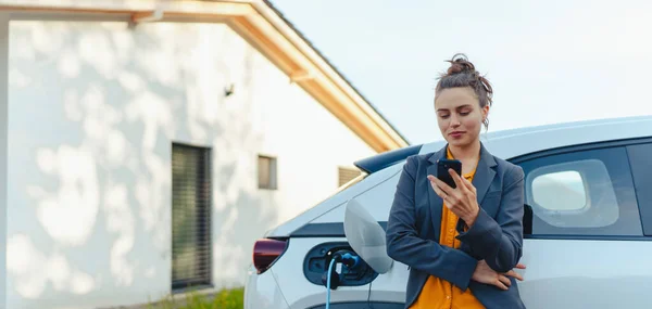 Young Woman Smartphone Waiting While Electric Car Charging Home Charging — Stock Photo, Image