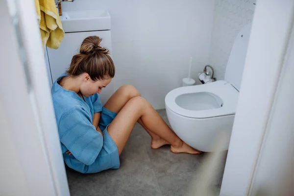 トイレの近くの床に座っている若い妊婦 — ストック写真