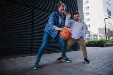 Man with down syndrome playing basketball outdoor with his friend. Concept of friendship and integration people with disability into the society. clipart