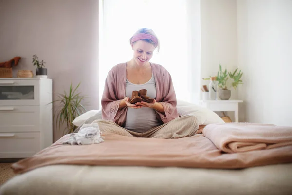 Счастливая Беременная Женщина Держит Маленькие Ботинки Своего Ребенка — стоковое фото