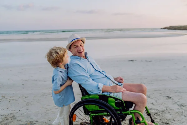 Anak Kecil Mendorong Kakeknya Kursi Roda Menikmati Laut Bersama Sama — Stok Foto