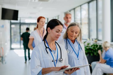 Yaşlı doktor genç meslektaşına tavsiye veriyor, hastane koridorunda tartışıyor. Sağlık hizmeti kavramı.