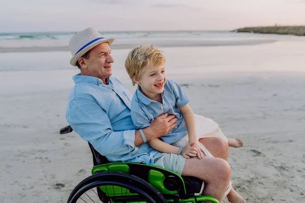 Küçük Çocuk Tekerlekli Sandalyede Büyükbabasıyla Eğleniyor Denizin Tadını Çıkarıyor — Stok fotoğraf