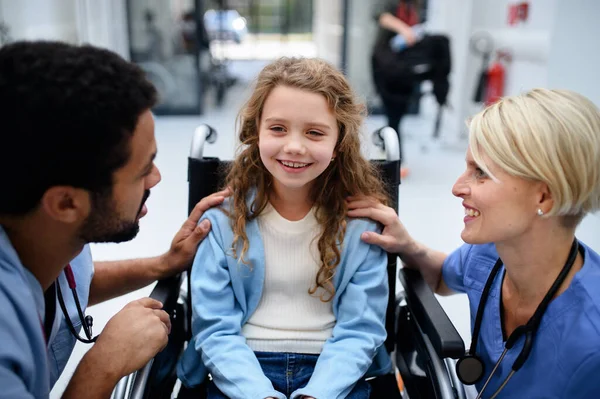 若い多人種間の医者と彼の同僚は車椅子の少女と話す — ストック写真
