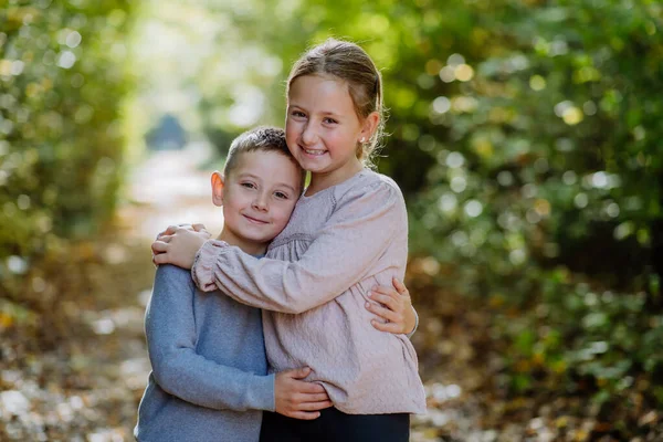 Portrait of little children, siblings, hugging in a forest.