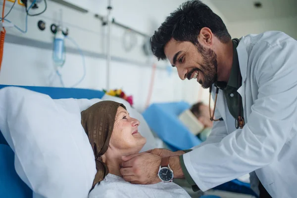 Ung Mellanösternläkare Ler När Han Undersöker Patienter Ett Sjukhusrum — Stockfoto