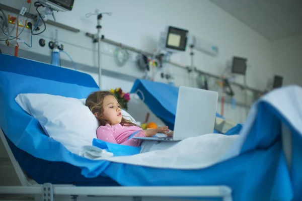 Küçük Hasta Kız Hastane Yatağında Tek Başına Yatıp Dizüstü Bilgisayar — Stok fotoğraf