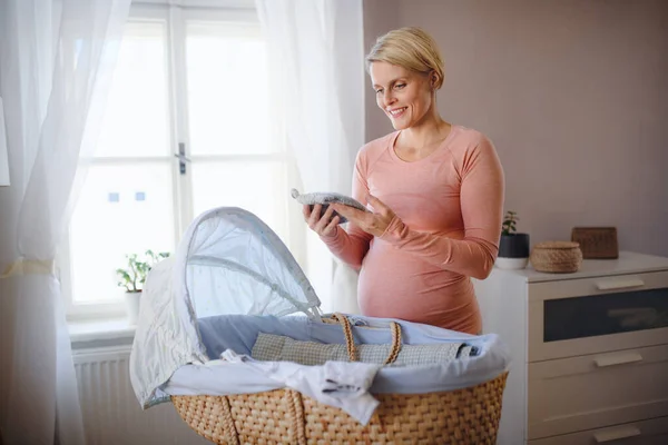 Mujer Embarazada Feliz Mirando Poca Ropa Bebé — Foto de Stock