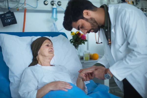 Young middle eastern doctor examining patient with cancer in a hospital.