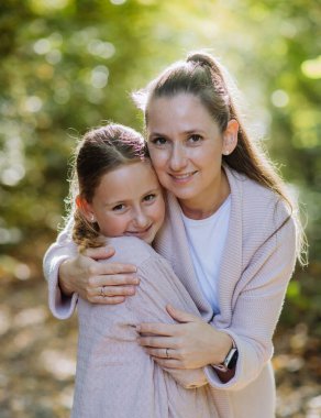 Portrait of mother with her daughter in a forest.