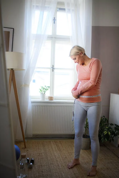 Happy Woman Measuring Her Pregnant Belly Her Apartment — Fotografia de Stock