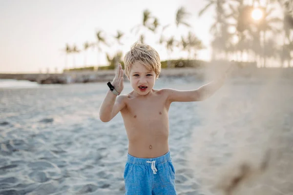 ビーチで砂と遊ぶ小さな遊び心のある男の子 — ストック写真