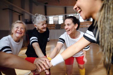 Spor salonunda el ele tutuşan bir grup çok nesilli kadın, spor takımı oyuncuları..