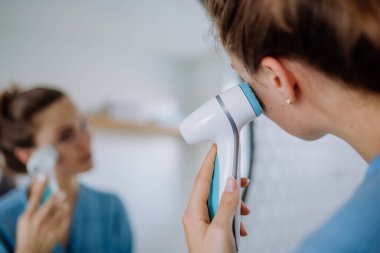 Yüzüne özen gösteren genç bir kadın, sabah güzellik rutini konsepti..