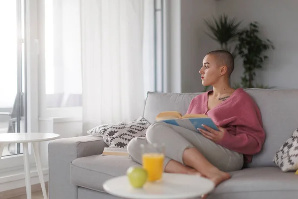 Young woman with cancer reading a book, cancer awareness concept.