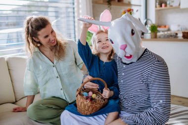 Little girl having fun with her mum and Easter rabbit, celebrating Easter.