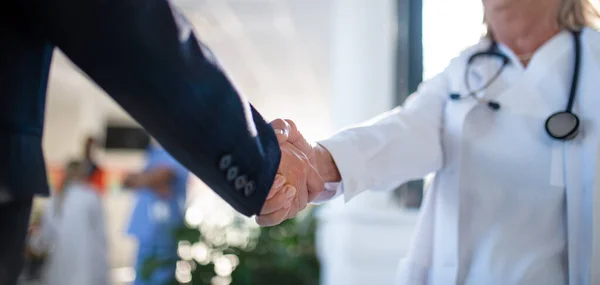 Close-up of handshake of doctor and business person.
