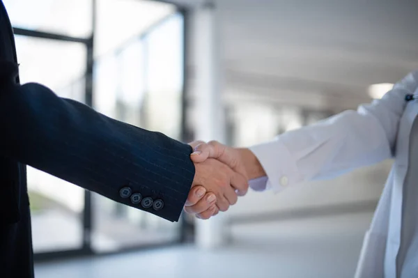 Close-up of handshake of doctor and business person.