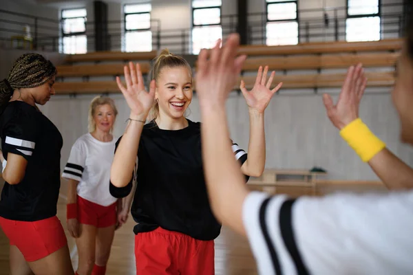 A group of young and old cheerful women, floorball team players, in gym cebrating victory.