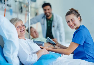 Young nurse measuring blood presure to senior patient. clipart