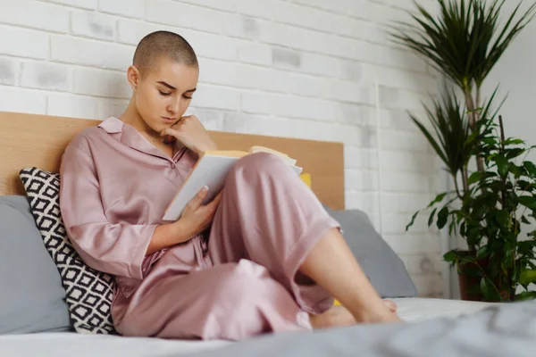 Young woman with cancer reading a book, cancer awareness concept.