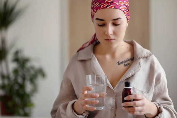 Young woman with cancer taking the pills, cancer awareness concept.