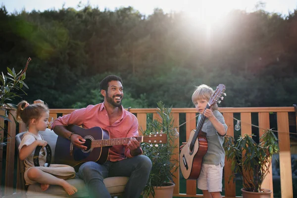 一个年轻的非洲裔美国人喜欢和小孩一起弹吉他 夏天他在花园里的庭院里用乐器伴奏 — 图库照片