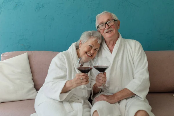 Happy Senior Couple Sitting Together Bathrobe Sofa Glass Wine Having — Stock Fotó