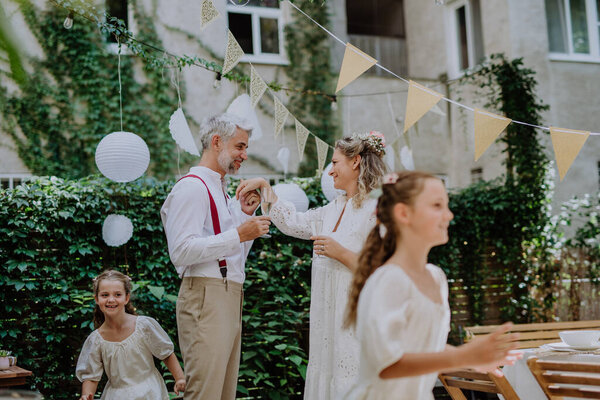 A mature bride and groom having a romantic moment at wedding reception outside in the backyard.