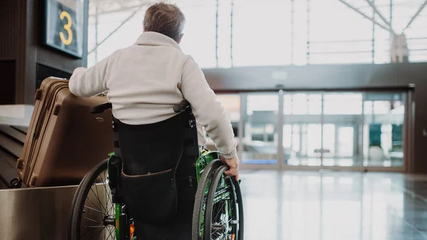 Takana Näkymä Mies Pyörätuolissa Lentokentällä Matkatavaroineen — kuvapankkivalokuva