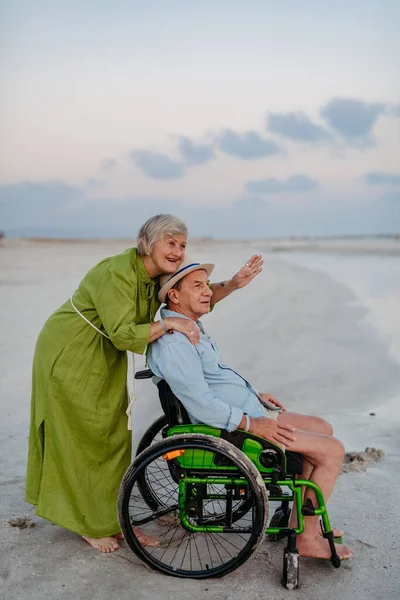 Starszy Mężczyzna Wózku Inwalidzkim Zabawia Się Żoną Nad Morzem — Zdjęcie stockowe
