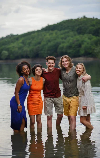 夏に手を取り湖に立つ多民族の若者たち — ストック写真