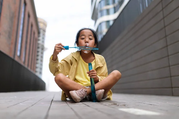 Little Girl Sitting City Blowing Bubbles — стоковое фото