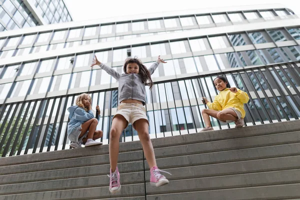 Two Girls Firends Jumping Concrete Wall City Low Angle View — Stockfoto