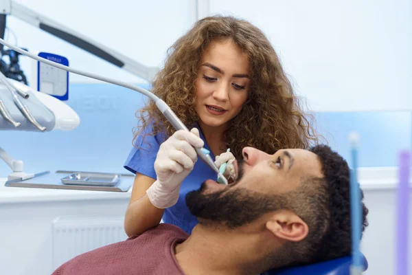Młoda Kobieta Dentysta Robi Badania Profilaktyczne Wielorasowego Mężczyzny — Zdjęcie stockowe