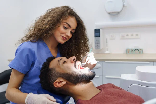 为多种族男子进行预防性检查的年轻女牙医 — 图库照片