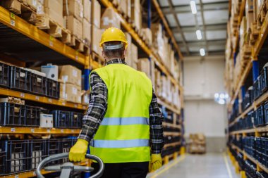 Male warehouse worker dragging the pallet truck.