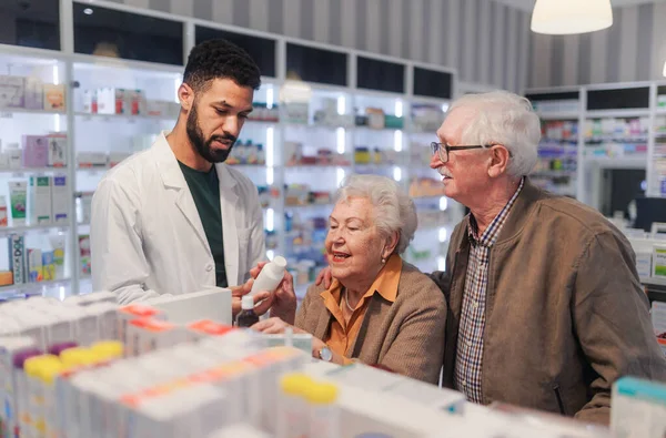 Junger Apotheker Hilft Senioren Paar Bei Medikamenteneinnahme — Stockfoto