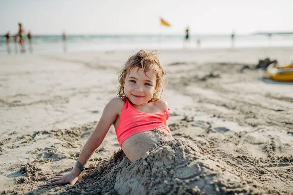 小女孩弯腰躺在沙滩上 享受着奇异的海上暑假 — 图库照片