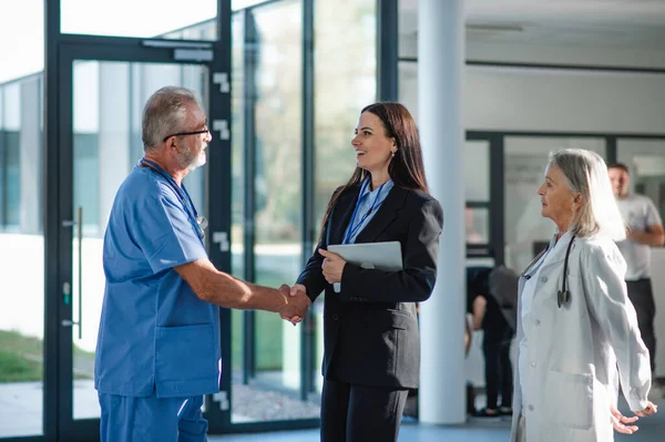在医院病房里 年轻的女商人和年长的医生握手 — 图库照片