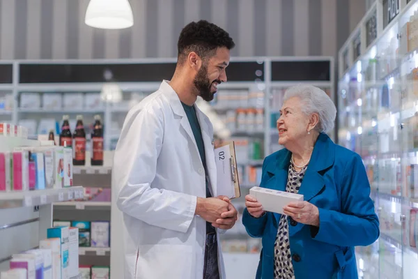 若い薬剤師は 高齢女性が薬を選ぶのを助ける — ストック写真