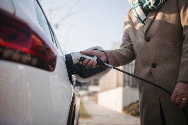 Elektrikli arabayı şarj eden son sınıf öğrencisine yakın çekim.