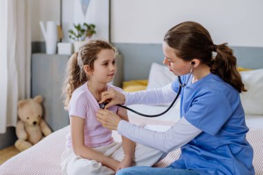 Hastane odasında küçük bir kıza bakan genç bir doktor..