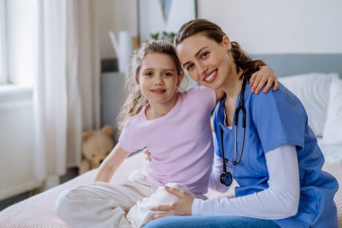 Hastane odasında küçük bir kıza bakan genç bir doktor..
