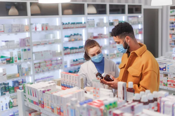 若い薬剤師は 顧客が薬を選ぶのを助ける — ストック写真