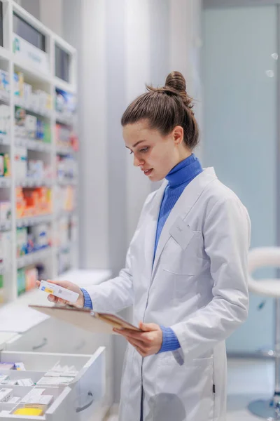 stock image Young pharmacist checking medicine stock in a pharmacy.