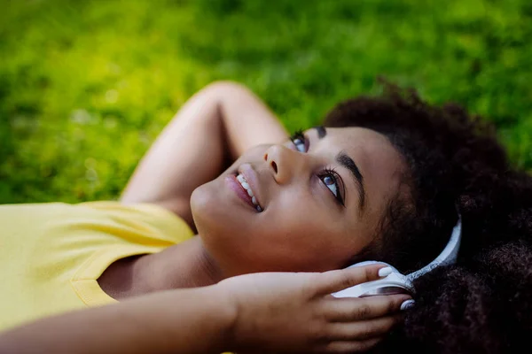 Multiracial Girl Lying Grass Enjoying Music Headphones Side View — Zdjęcie stockowe