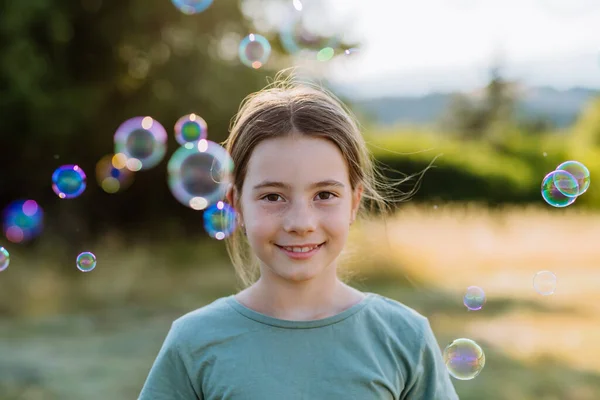 一个美丽的小女孩在大自然中微笑的画像 后面是气泡 — 图库照片