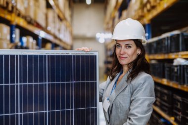 Portrait of manager holding solar panel in a warehouse. clipart