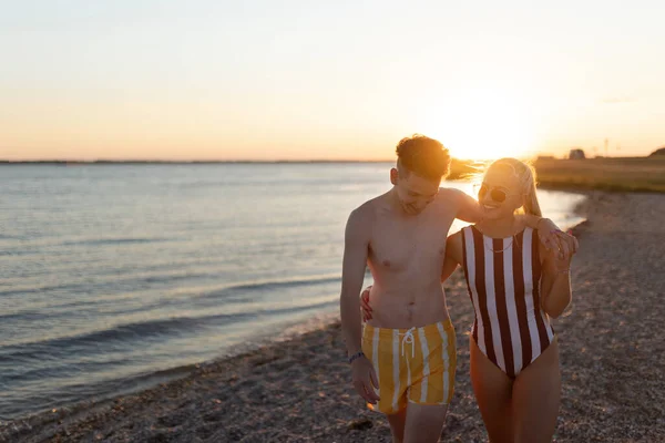 Happy Young Couple Stripped Swimsuits Walking Beach Sunset — ストック写真